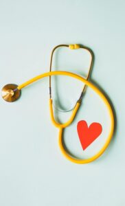 pexels-photo-4386467-4386467 Yellow stethoscope arranged with a red heart cutout on a light green background, symbolizing heart health.